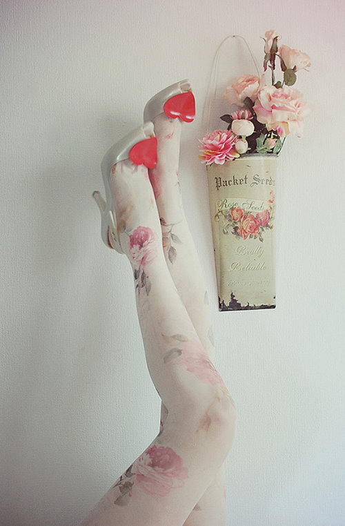 Девушка подняла вверх ноги в белых колготах с розами