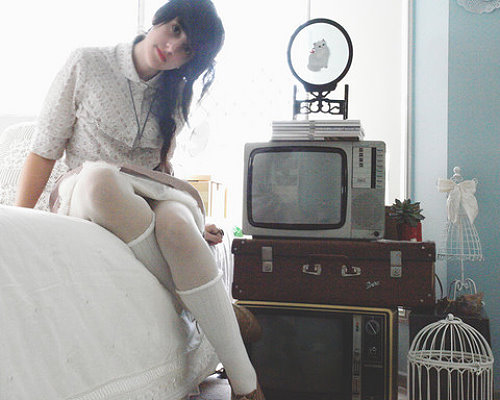 Девушка сидит на диване возле старого телевизора в белых колготах