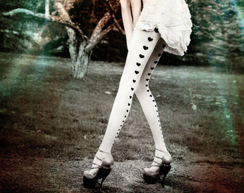 Девушка с очень длинными ногами в белых колготках с сердечками сзади