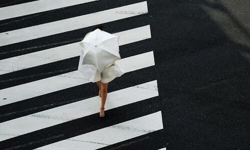 девушка в белом платье под белым зонтом переходит дорогу по зебре вид сверху под дождем