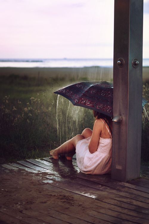 девушка под проливным дождем прячется под зонтом