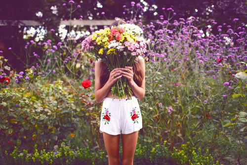 девушка прячется в букете цветов в шортиках в вышивкой