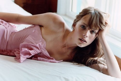 девушка в розовом платье лежит на боку на кровати домашнее фото