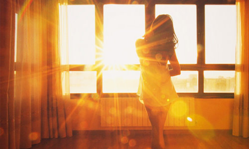 силуэт девушки в солнечных лучах дома у окна