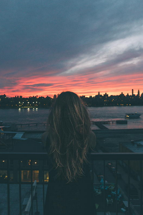 девушка с мелированными волосами на закате в свете ночного города