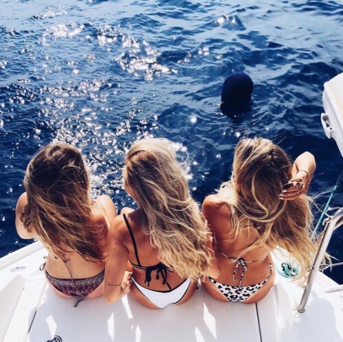 три светловолосые девушки вид сверху в купальниках плывут на яхте