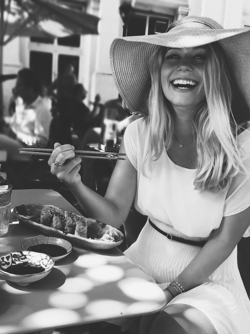 блондинка в шляпе смеется с японскими палочками для еды