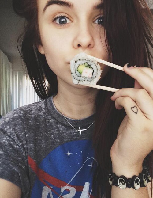 девушка с синими глазами держит суши у рта