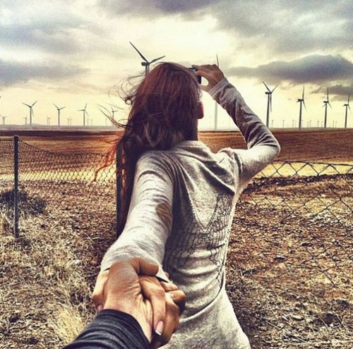 девушка с парнем за забором фотографируют ветряные мельницы