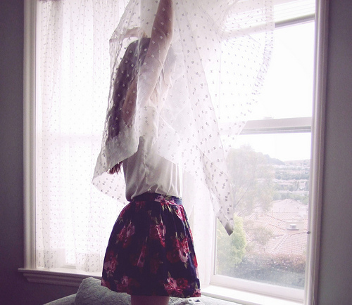 девушка у окна за занавеской без лица в юбке