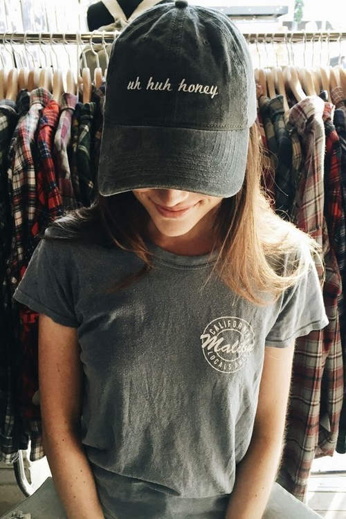девушка в серой кошлатой футболке и кепке uh huh honey в магазине