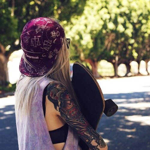 девушка скейтер спиной с татуировкой на всю руку с кепкой задом наперед