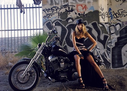 байкерша на мотоцикле в кепке на фоне граффити