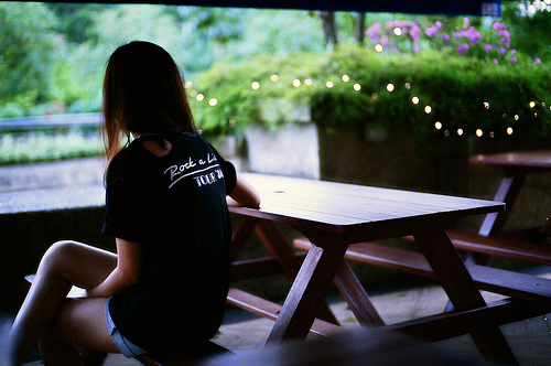 девушка без лица со спины за столиком кафе в черной футболке