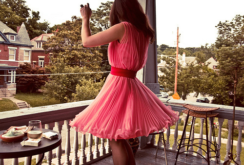 дівчина в рожевому пишній сукні крутиться на ганку