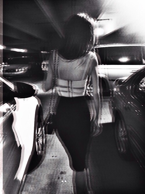 девушка в подземном паркинге со спины с сумочкой направляется к своему автомобилю нечеткое заблюренное фото