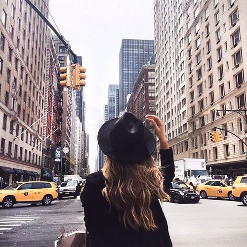 дівчина спиною у місті в чорному капелюсі
