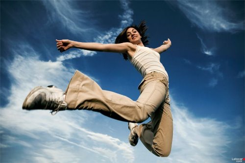 девушка в прыжке на фоне синего неба с красивыми облаками