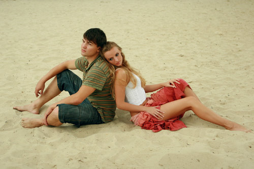 спина к спине девушка с парнем на песке
