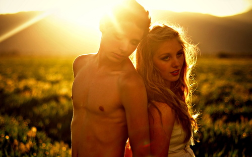 парень с девушка спиной к спине в поле в солнечных лучах