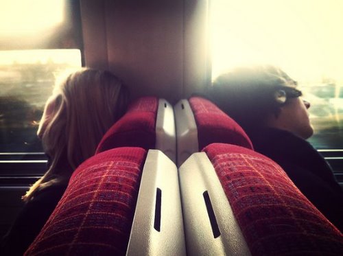 девушка и парень в поезде спина к спине в наушниках