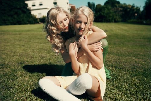 две беленькие сестры обнимаются на лужайке