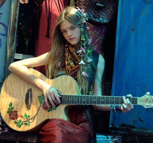 блондинка с цветами в волосах играет на гитаре
