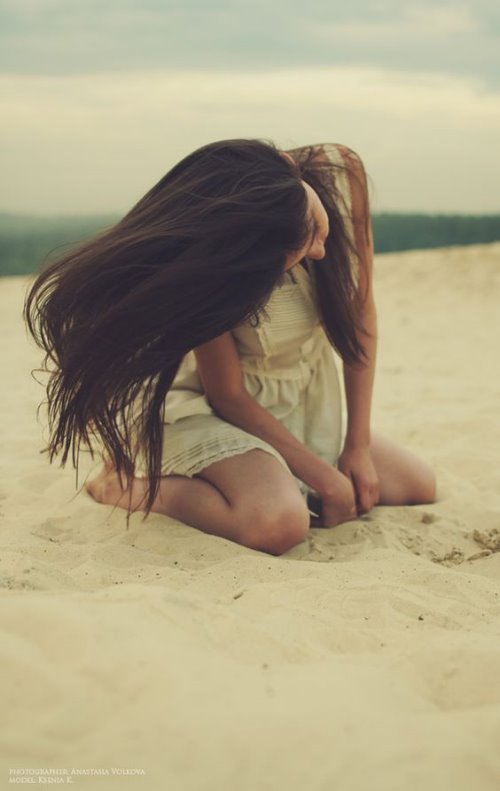 девушка на песке на море в ветренную погоду