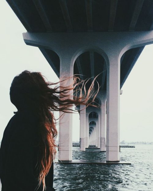 девушка под мостом на море, ветер развевает волосы