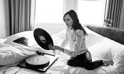 девушка сидит на кровати с музыкальными пластинками