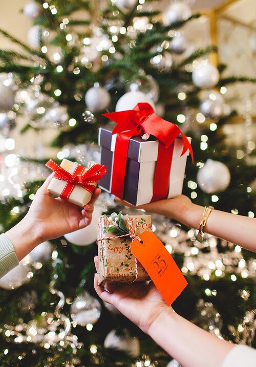 подружки держат свои подарки под новогодней елкой