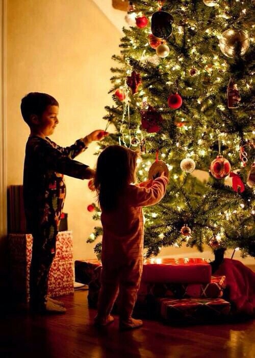 маленькие детишки украшают елку