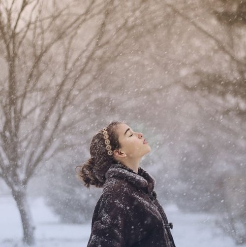 девушка ловит снежинки первого снега в лесу