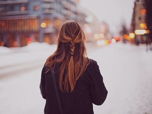 девушка без шапки зимой под снегом гуляет по городу