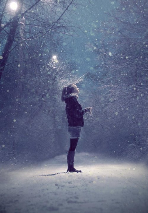 девушка с хвостом ловит первый снег под фонарем в парке