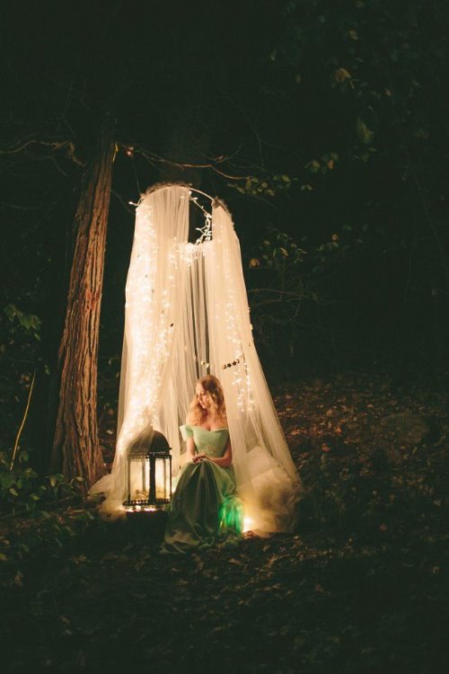 девушка сидит в лесу в свете фонаря