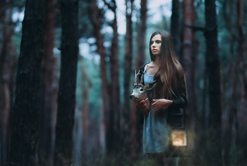 девушка в лесу с головой оленя и фонарем