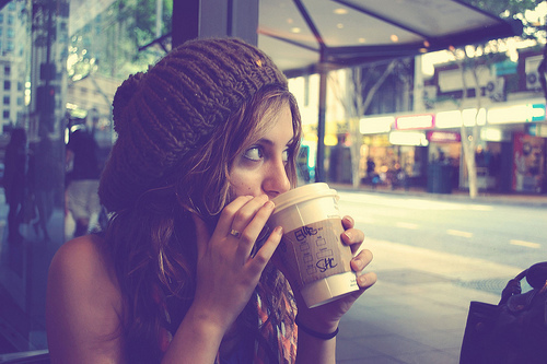 девушка с длинными волосами в вязанной шапке пьет кофе
