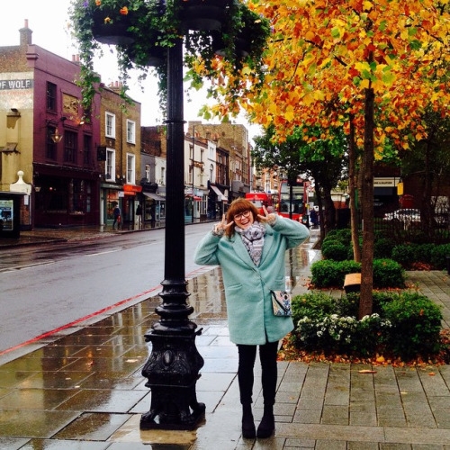 радостная девушка в голубом пальто осенью под дождем