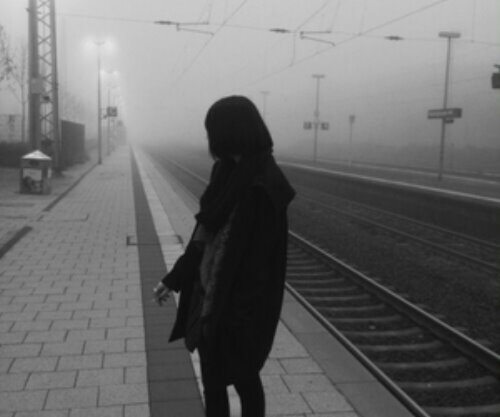 девушка ждёт поезд на вокзале осенью под дождем в тумане