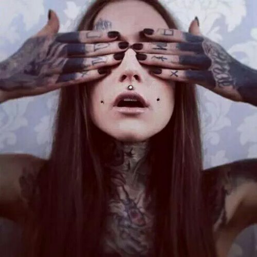 девушка с пирсингом и татуировками закрыла глаза руками