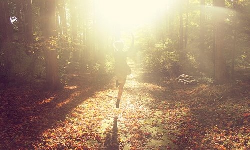 девушка бежит в припрыжку навстречу солнцу в осеннем лесу