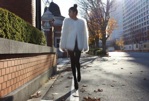модная девушка в белой полушубке осенью идет по городу