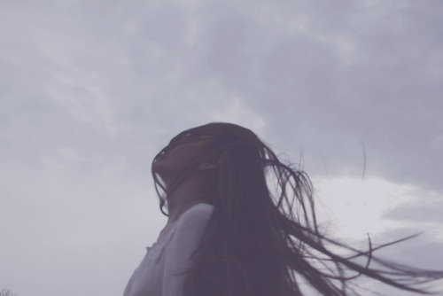 девушка с длинными волосами на фоне серого неба
