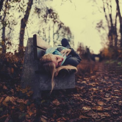 блондинка лежит на скамейке в осеннем парке в непогоду грустная фотосессия