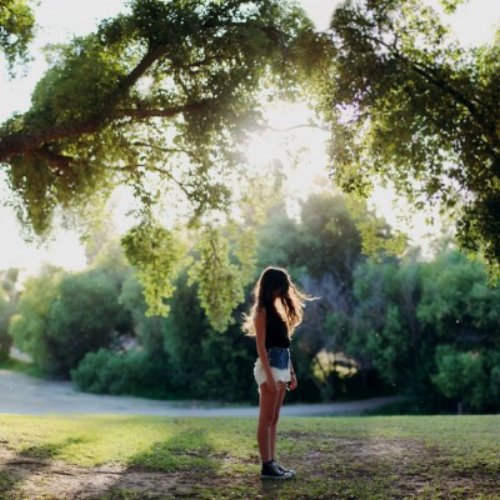 девушка стоит под деревом летом