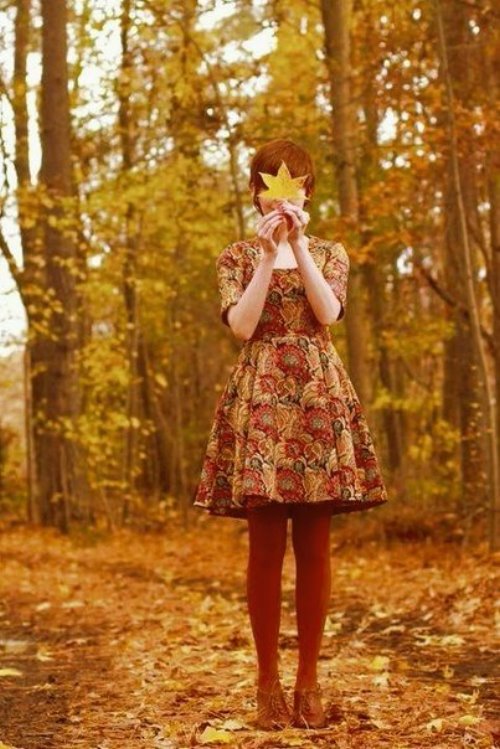 девушка в платье и красных колготках в лесу прикрылась листиком