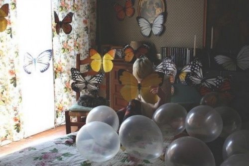 девушка прячется за бабочкой среди воздушных шаров на кровати в комнате