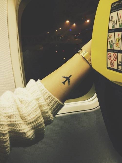 девушка с татуировкой самолета на руке на посадке