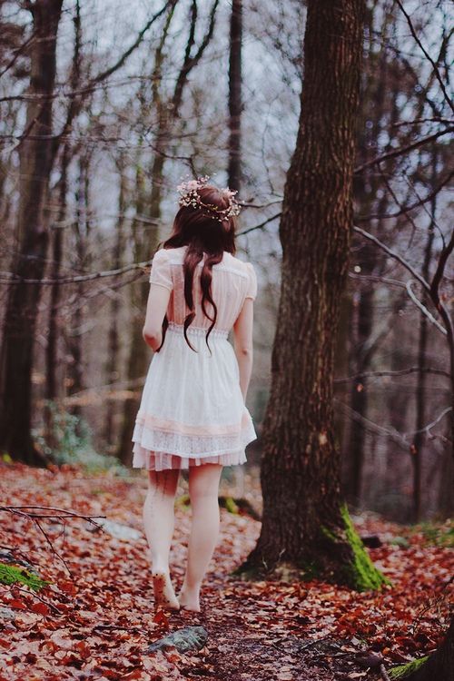 девушка в белом платье со спины с татуировкой на ноге в парке осенью